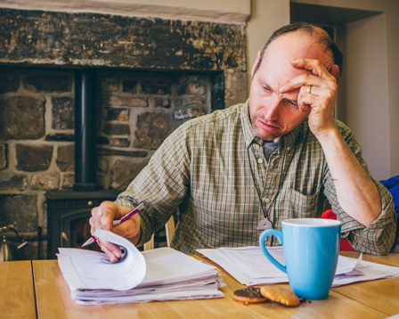 A man looking at paperwork at his dining room table