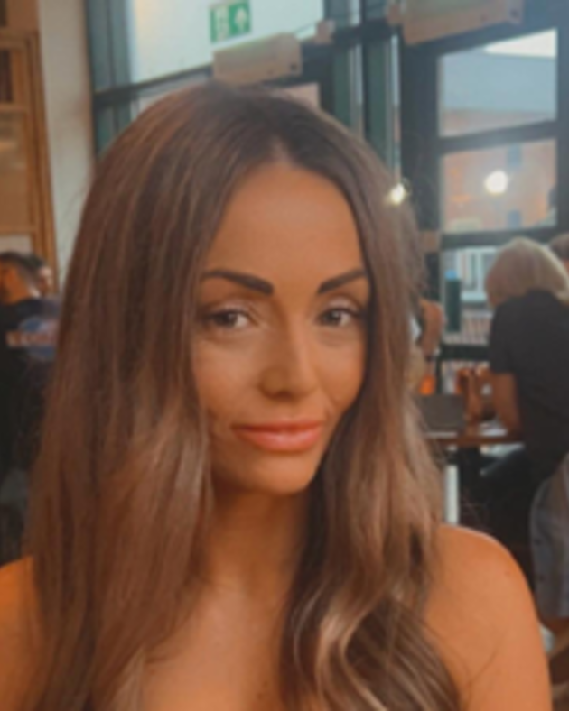 A young woman with long dark hair falling over her shoulders standing in a bar