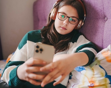 A young girl sitting on her bed using a mobile phone 