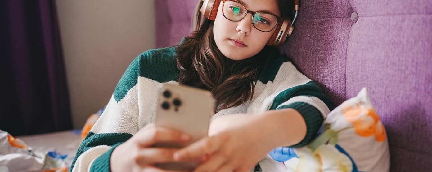 A young girl sitting on her bed using a mobile phone 