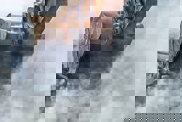 Excavator demolishing wall of an old house.