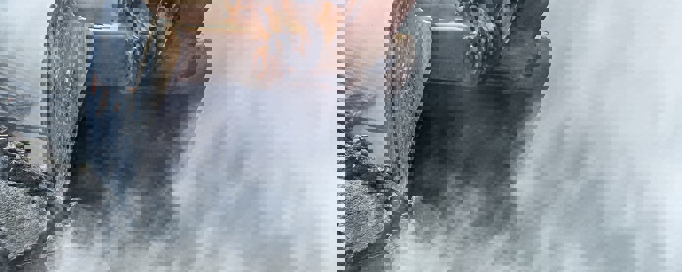 Excavator demolishing wall of an old house.