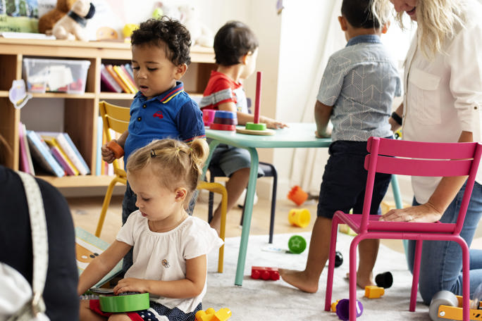 Nursery children playing with teacher