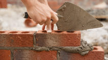 Bricklayer builder working laying red bricks and blocks on construction site