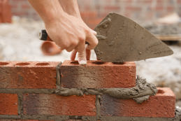 Bricklayer builder working laying red bricks and blocks on construction site