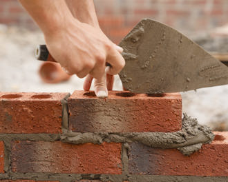 Bricklayer builder working laying red bricks and blocks on construction site