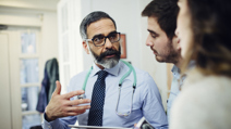 GP with stethoscope discussing test results with a couple during a clinic consultation