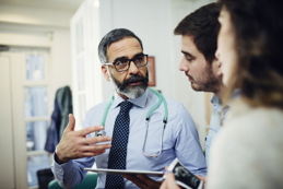 GP with stethoscope discussing test results with a couple during a clinic consultation