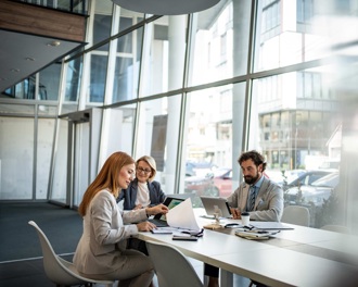 Three colleagues sitting at a desk in a contemporary office