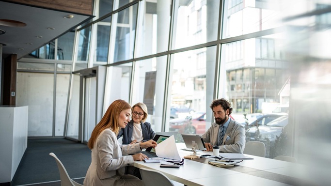 Three colleagues sitting at a desk in a contemporary office