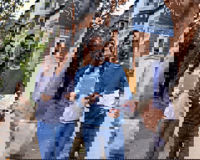 A real estate agent presenting house blueprints to a couple, discussing the property for sale.