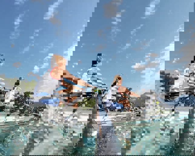 Two female athletes rowing lake