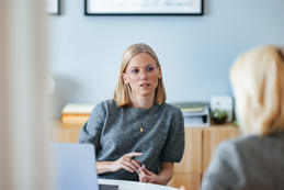 Two colleagues having a professional discussion in a modern, well-lit office, brainstorming ideas and strategies collaboratively.