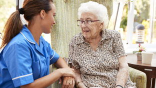 Domiciliary caregiver supporting an elderly woman