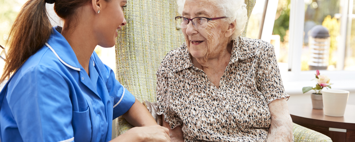 Domiciliary caregiver supporting an elderly woman