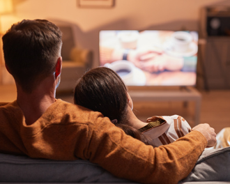 Couple watching tv on a couch.