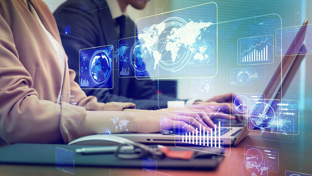 Two business professionals are working on laptops side by side, with various transparent digital data graphics.