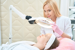 cosmetologist looks through magnifying glass