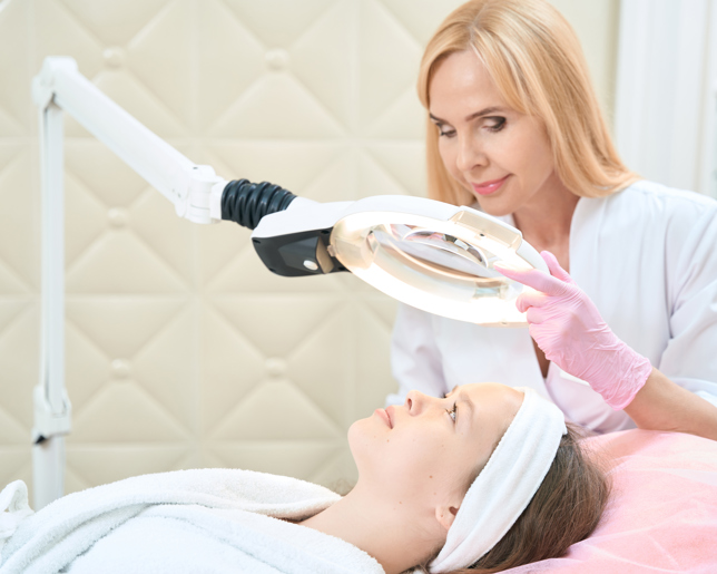 cosmetologist looks through magnifying glass