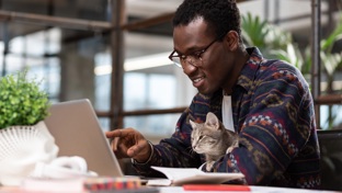 Man sitting at his laptop with a cat on his lap
