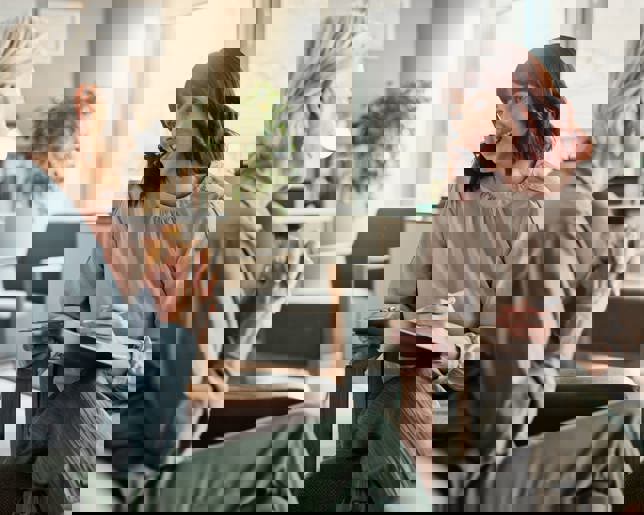 Senior woman consulting with a psychologist holding a clipboard for counseling and support in an office.