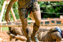 man rising out of barbwire mud pit in obstacle course