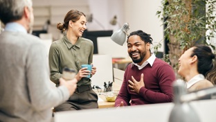 Four colleagues laughing together in an office