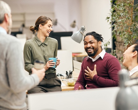 Four colleagues laughing together in an office