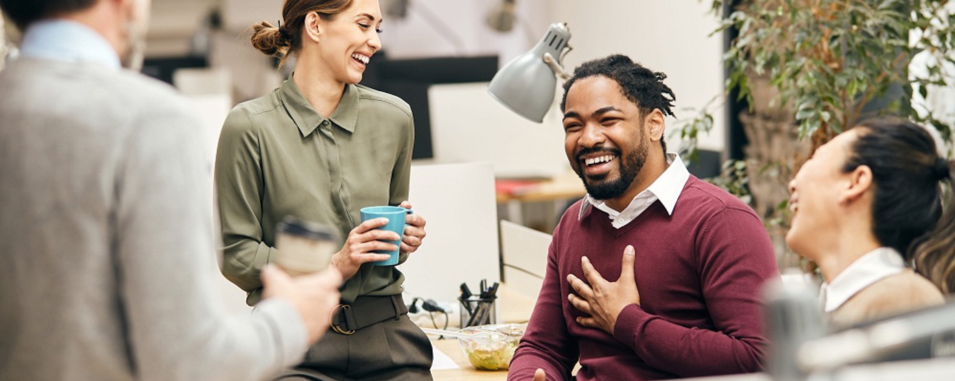Four colleagues laughing together in an office