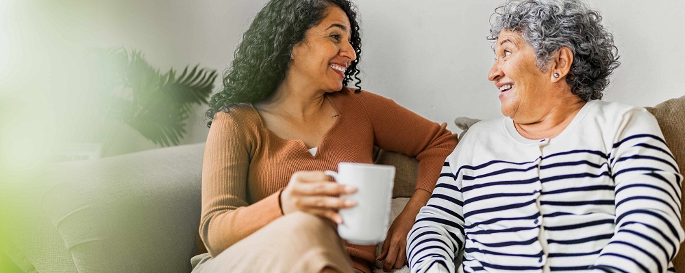 Two ladies it smiling on a sofa