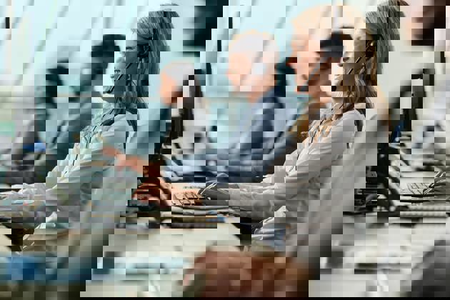 Businesswoman and her colleagues working on desktop PC in a call center