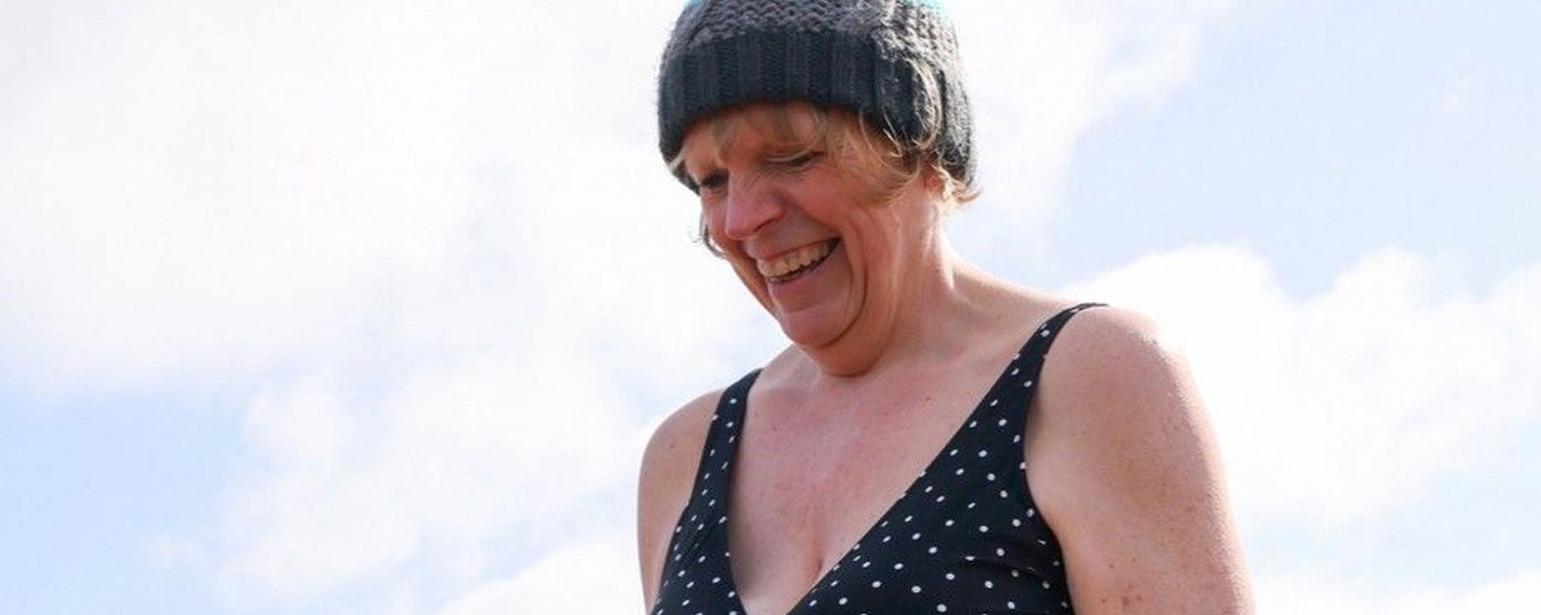 a very happy women wearing a beanie hat and a swimsuit