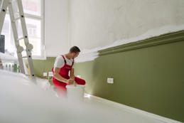 A professional house painter painting walls in the apartment