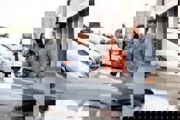 Latin American salesman showing a car to a couple 