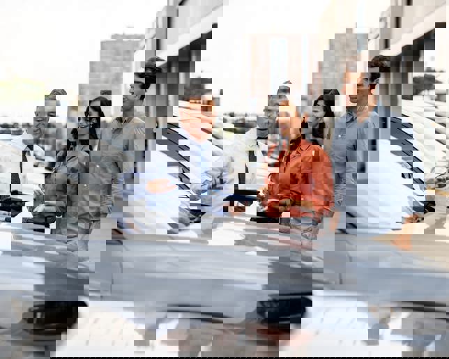 Latin American salesman showing a car to a couple 