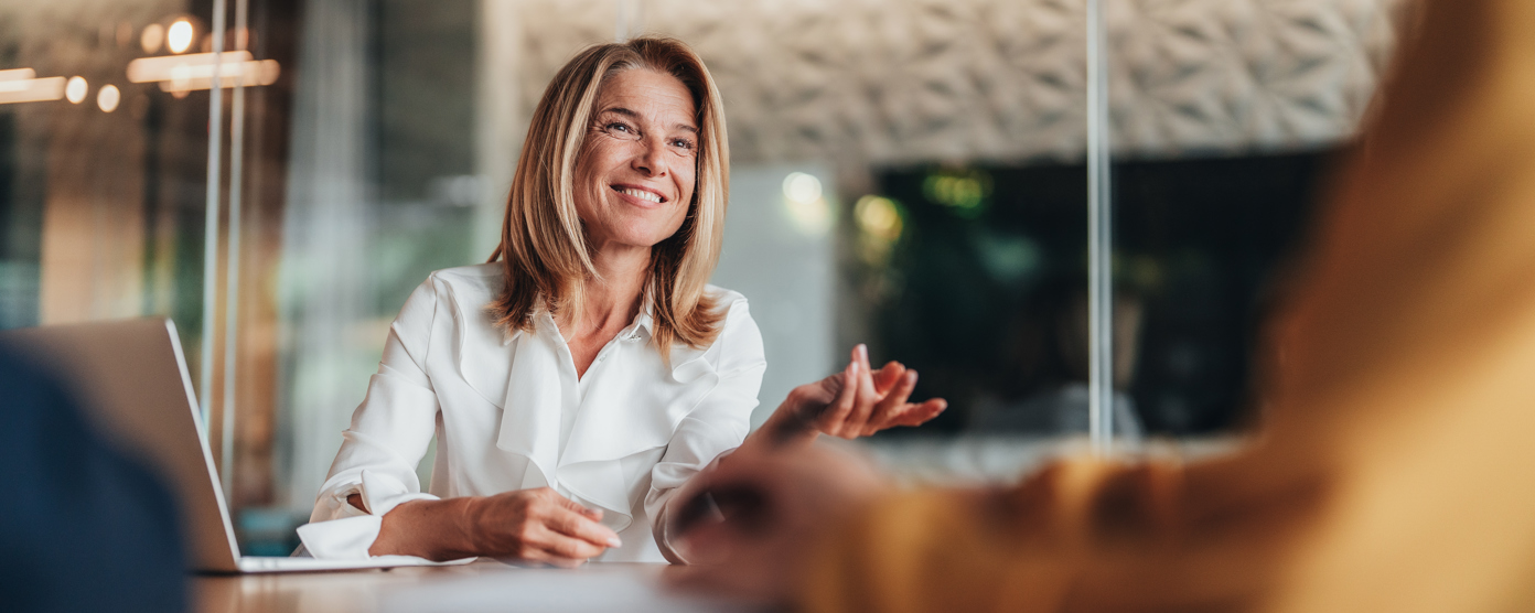 Female dressed smartly in a business meeting using hand gestures and smiling 