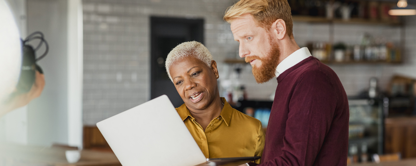 Two colleagues looking at a laptop together, working in a relaxed environment