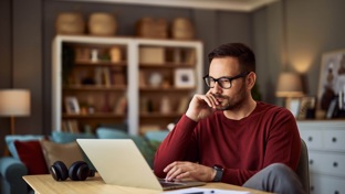 Man at his kitchen table using laptop