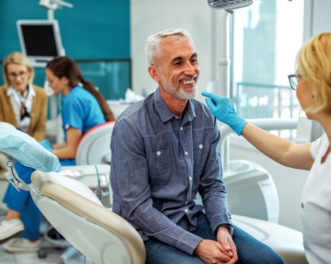 An older man sits on a dentist chair and smiles in a private dental clinic