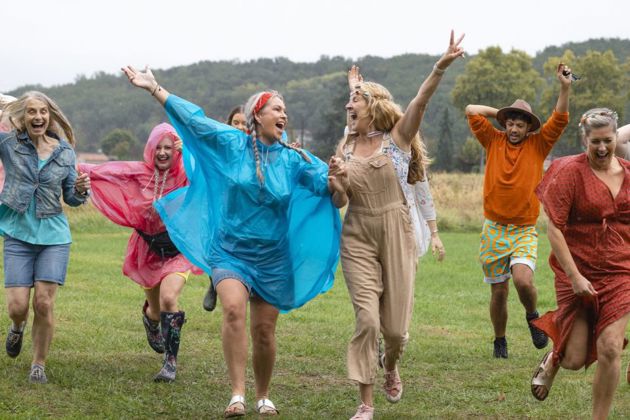 Group of people happily running with their arms in the air on a wet day