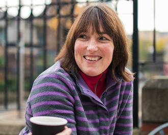 2 smiling women enjoying drinks in paper cups