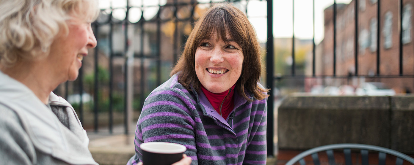2 smiling women enjoying drinks in paper cups