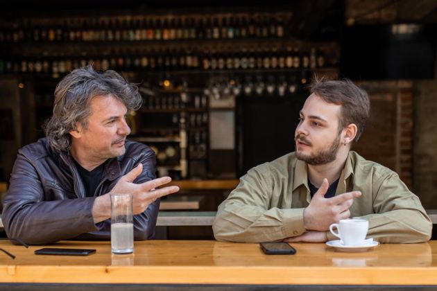 Two men having a chat sat in window seats on an elevated counter