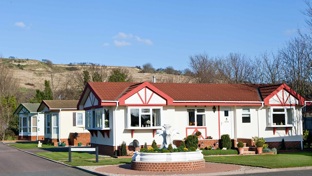 A park home with a fountain in front of it on a sunny day