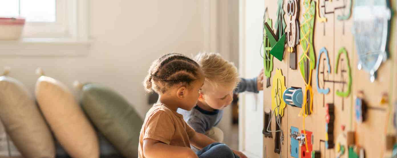 Two toddlers playing a sensory activity in a nursery.