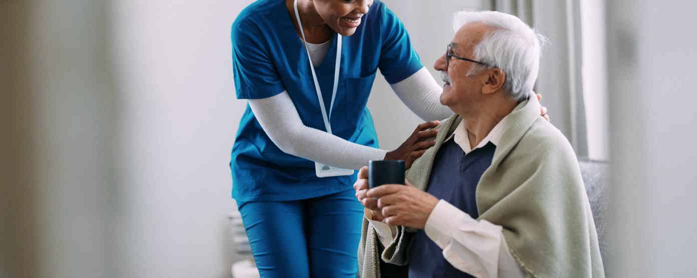 Care worker talking with an elderly man in a home.