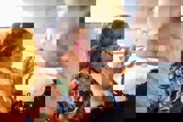 A young girl getting glitter painted on her face