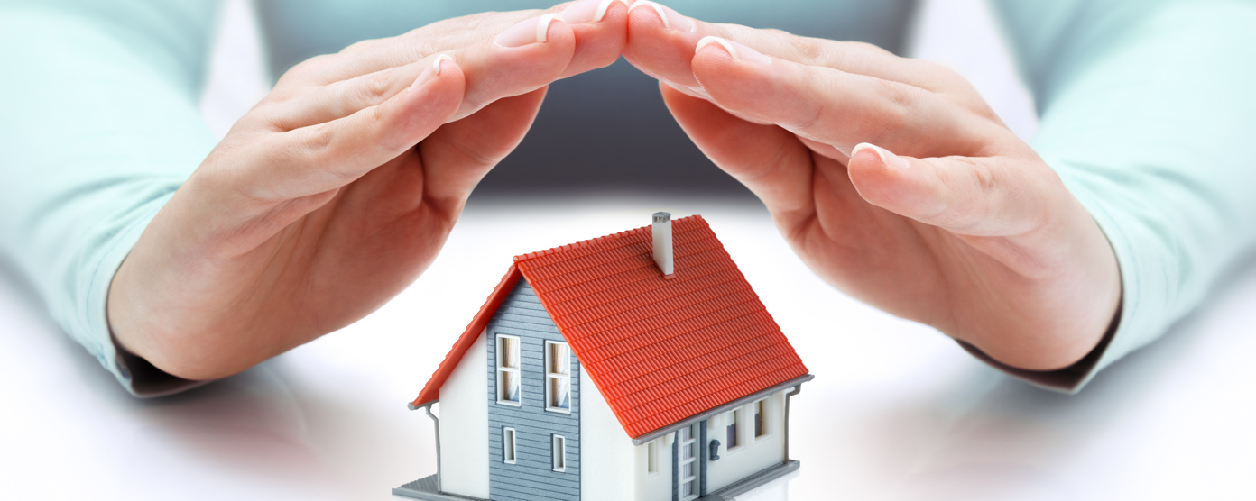 A pair of hands supports a tiny house, representing the idea of safeguarding homes through protection or insurance.
