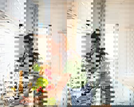 Woman preparing healthy meal laptop recipe