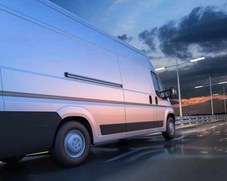 White delivery van driving along a wet highway at sunset with motion blur